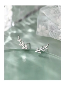 Macro view of silver leaf branch stud earrings with zircon on a rippled glass texture