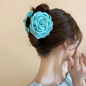 Detail der blauen Organza-Blumen-Haarklammer mit Perlen an der Frisur des Modells