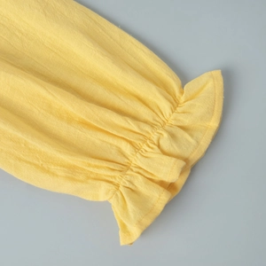 Detail of yellow ruffle cuff showing the textured linen fabric and stitching on summer dress