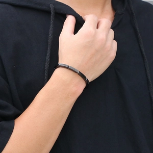 Minimalist black segmented stainless steel bracelet for men worn on wrist over a hoodie