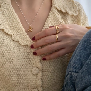 Close-up of a gold heart ring and balloon dog pendant necklace on a model