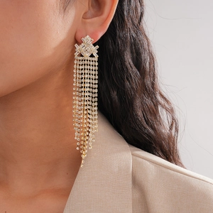 Macro shot of gold geometric tassel earrings with zircon crystals worn by a model