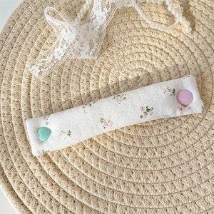 Detailed view of quilted floral fabric cable organizer with heart-shaped buttons