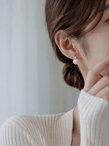 Detailed close-up of a large natural freshwater pearl stud earring on model's ear