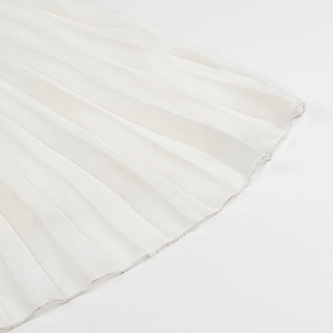 Detailed macro view of white pleated chiffon fabric and fine hem stitching on the dress