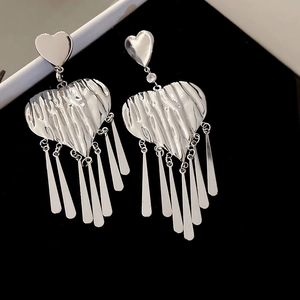 Macro shot of silver heart fringe earrings with layered tassel details on black velvet
