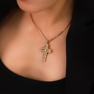 Detailed view of 18K gold box chain with sparkling diamond-set cross pendant on a model