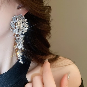 Gros plan de boucles d'oreilles pendantes géométriques en strass argentés sur un mannequin