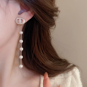 Detail of elegant gold tassel earrings featuring zircons and five cascading pearls