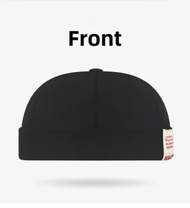 Front view detail of a black brimless docker hat with a decorative side patch tag