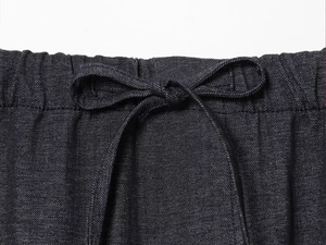 Gros plan détaillé d'un pantalon en denim bleu foncé avec taille élastique et cordon