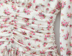 Detail of waist ruffles and floral print on white chiffon V-neck long sleeve dress