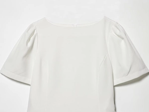 Dettaglio dell'abito bianco a spalle scoperte con maniche a sbuffo e zip retro