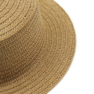 Detailed close-up of woven paper straw texture and spiral stitching on the flat boater hat