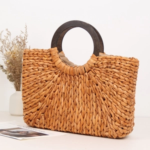 Handmade corn husk woven beach bag with round wooden handles and large capacity