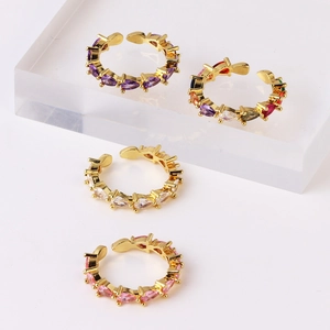 Detailed arrangement of four gold-plated open rings with colorful teardrop zircons