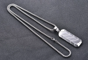 Detailed view of silver stainless steel geometric pendant with tire pattern on box chain