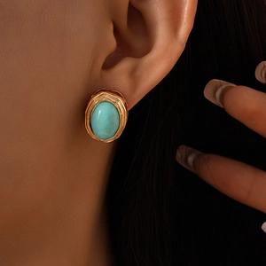 Detail of vintage gold stud earring with oval turquoise stone on model's ear