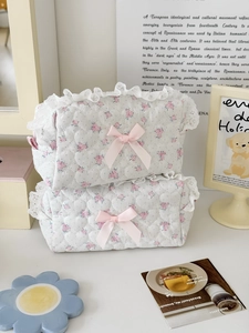 Macro detail of quilted heart texture and delicate lace edge on pink floral makeup bag