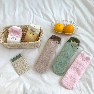 Close-up of cozy coral fleece socks with cute cartoon animal patterns in soft pastel colors