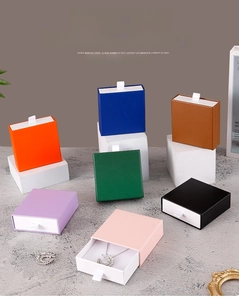 Detailed view of multi-color drawer jewelry boxes with white ribbon pulls on display stand
