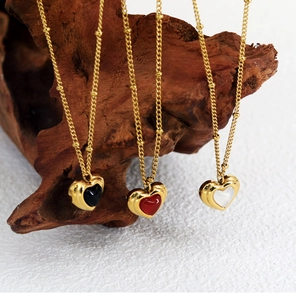 Detailed close-up of heart-shaped pendants in black, red, and pearl on vintage wood stand