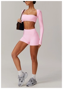 Detailed view of pink three-piece yoga set including long sleeve top and high waist shorts