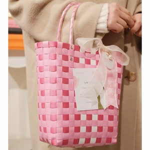 Pink and white checkerboard woven tote bag with a large satin bow and holiday gift card