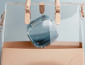 Portable 3-layer dental retainer case in teal blue inside a stylish transparent handbag