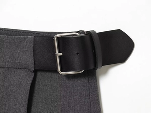 Vue détaillée du pantalon gris avec une large ceinture en cuir noir et boucle en métal argenté