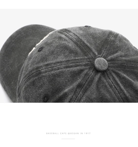 Top detail of washed grey cotton baseball cap with ventilation holes and stitching