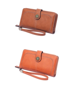 Detail view of brown and orange long wallets with laser-cut patterns and petal metal buckle