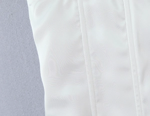 Gros plan détaillé du tissu en satin blanc lisse avec coutures verticales sur le haut