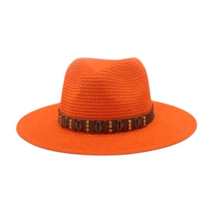 Détail d'un chapeau de paille orange avec une bande décorative cloutée style bohème