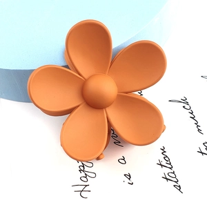 Macro detail of the orange matte flower hair claw clip with a frosted texture finish