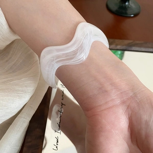 Macro detail of white wavy acrylic bracelet with cloud-like marble texture
