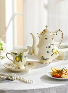 Detail of vintage ceramic lemon and butterfly teapot with elegant gold-rimmed edges