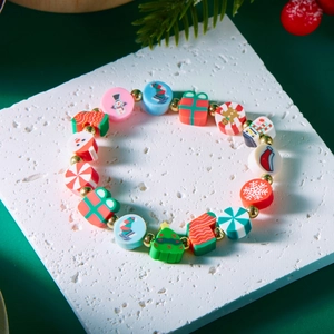 Detailansicht Weihnachtsarmband mit Weihnachtsmann- und Schneemann-Anhängern auf weißem Brett