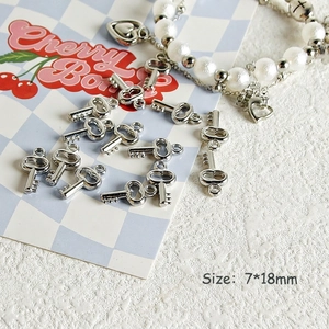 Detail of silver Y2K bear and butterfly charms with a white pearl heart bracelet