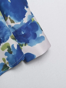 Détail du motif floral bleu sur poignet de chemise en satin blanc avec couture nette