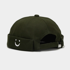 Detail of olive green docker hat featuring white smile embroidery and metal buckle