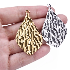 304 stainless steel textured leaf pendant held by hand in gold and silver finish