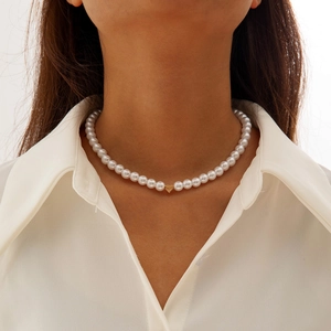 Close-up of elegant pearl necklace with a central golden heart pendant on a woman neck