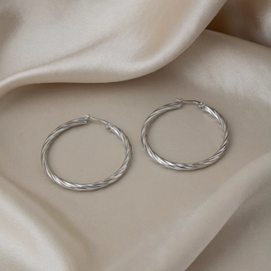 Detailed close-up of twisted rope hoop earrings with shiny polished mirror finish