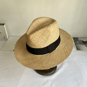 Macro detail of natural straw Panama hat with fine weave and wide black ribbon trim