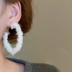 Détail d'un mannequin portant une boucle d'oreille créole géométrique en maille blanche