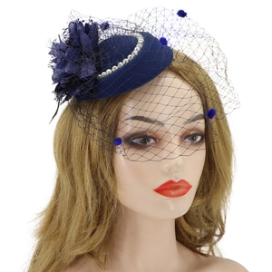 Detail view of navy blue fascinator with mesh veil, blue pom-poms and elegant pearls