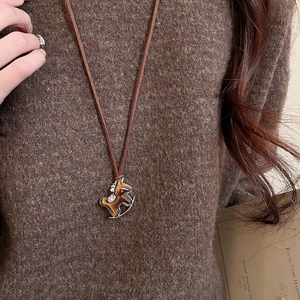Detail view of a zircon horse necklace styled with a warm brown knit sweater
