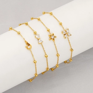 Macro detail of gold plated bracelets featuring star, butterfly and flower pendants
