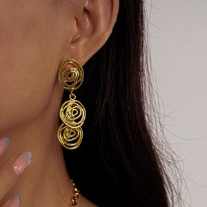 Vue détaillée de boucles d'oreilles triple spirale dorées portées par un mannequin